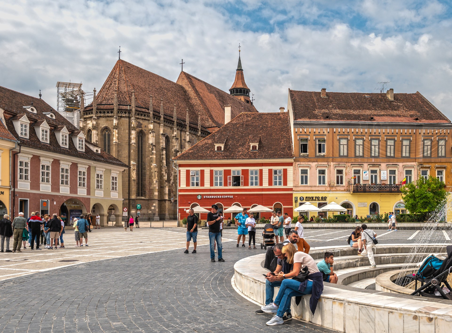 Young people relaxing by the fountain on Council Square in Brasov with the Black Church behind